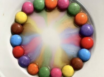 des bonbons s'étendent dans du lait au cours d'une expérience scientifique
